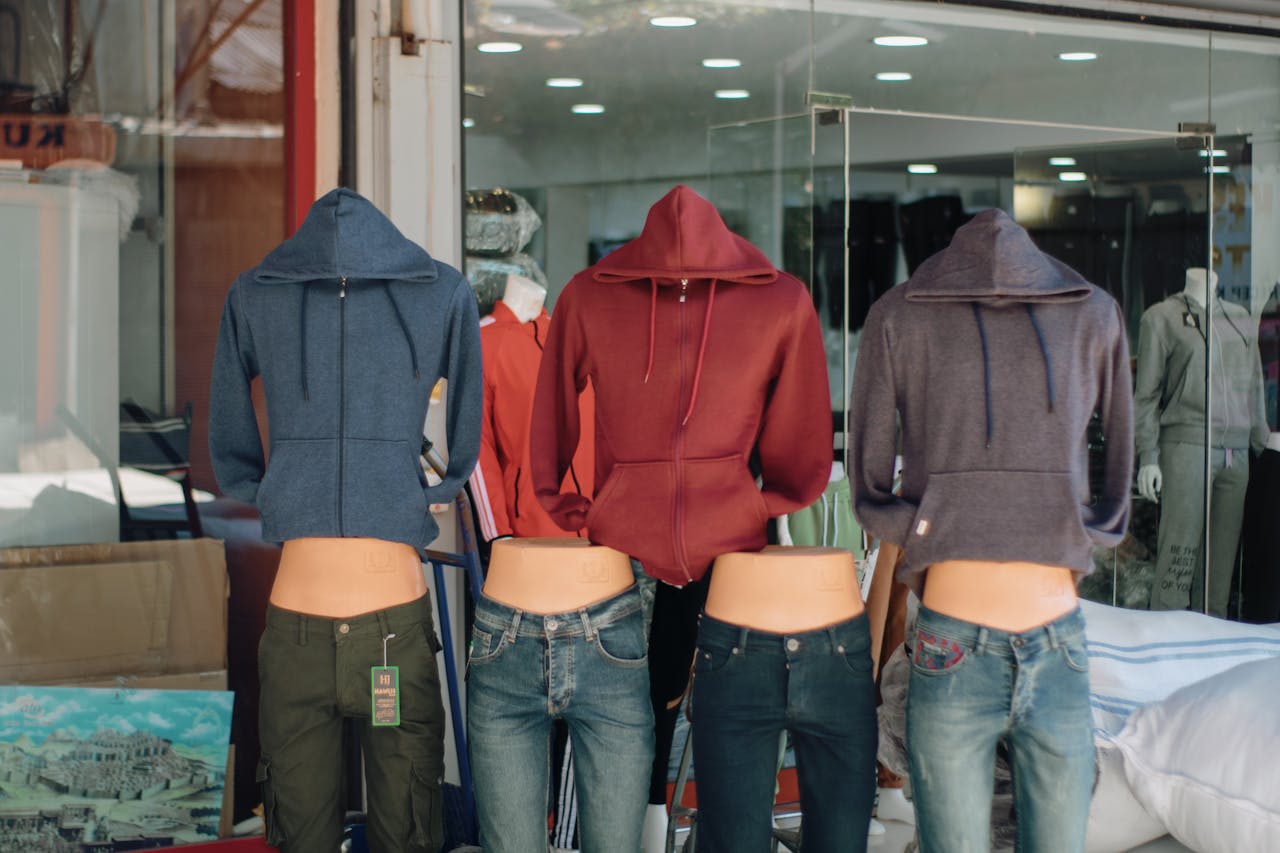 Services-03 Hooded sweatshirts and jeans displayed on mannequins in a retail storefront window.