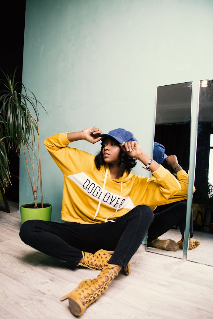 Fashionable woman poses with a trendy bucket hat and hoodie, showcasing modern style indoors.