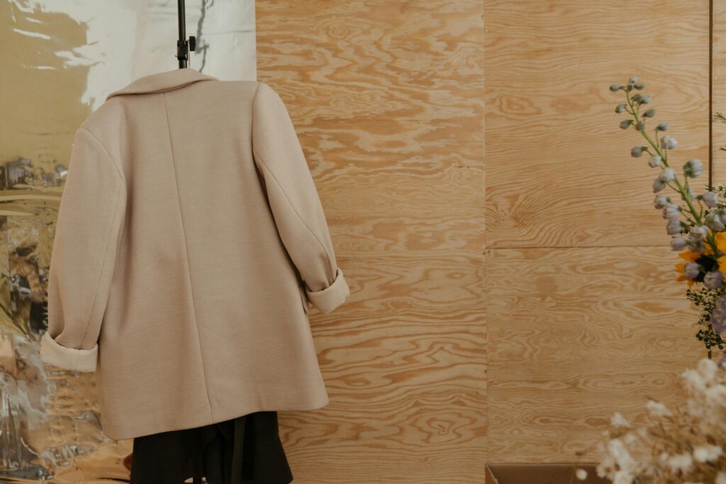 Elegant coat displayed against a textured wooden backdrop with floral accents.