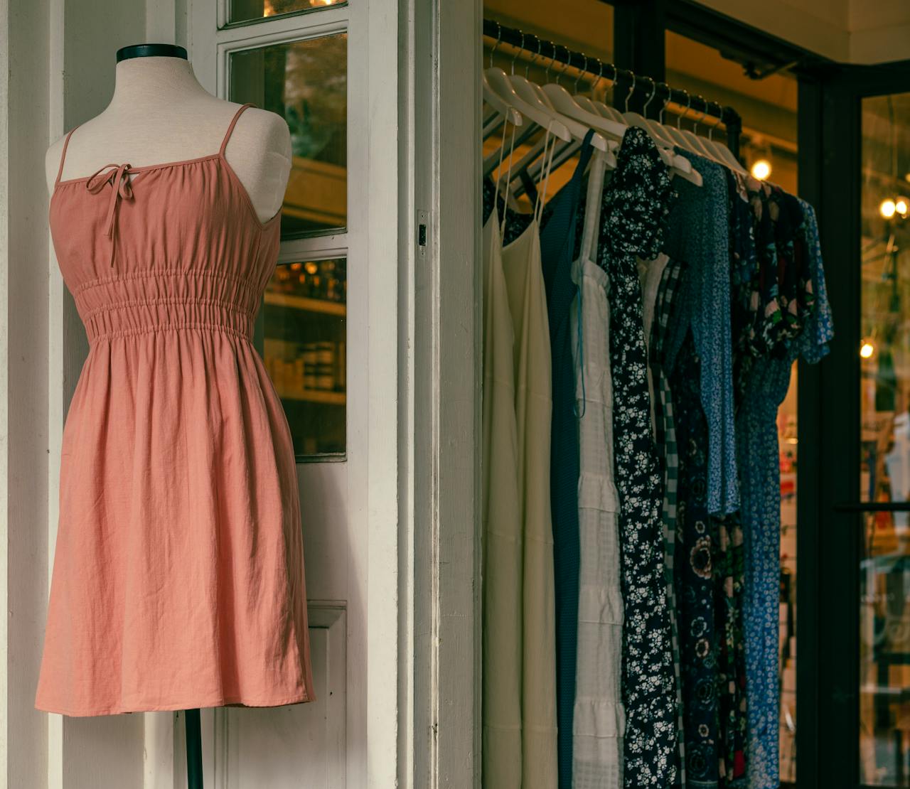 Services-02 Mannequin with a pink dress and clothing rack in a stylish boutique.